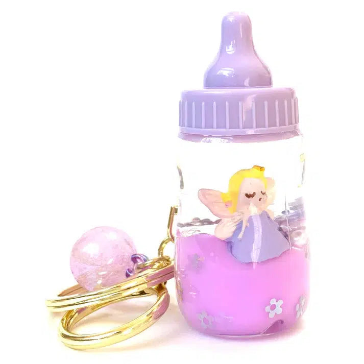 This charming keychain showcases a magical baby bottle with a purple cap, filled with pink liquid and housing a fairy figure. Attached to a gold key ring with a pink bead, it's an enchanting key charm that adds a whimsical touch to your collection of assorted designs.