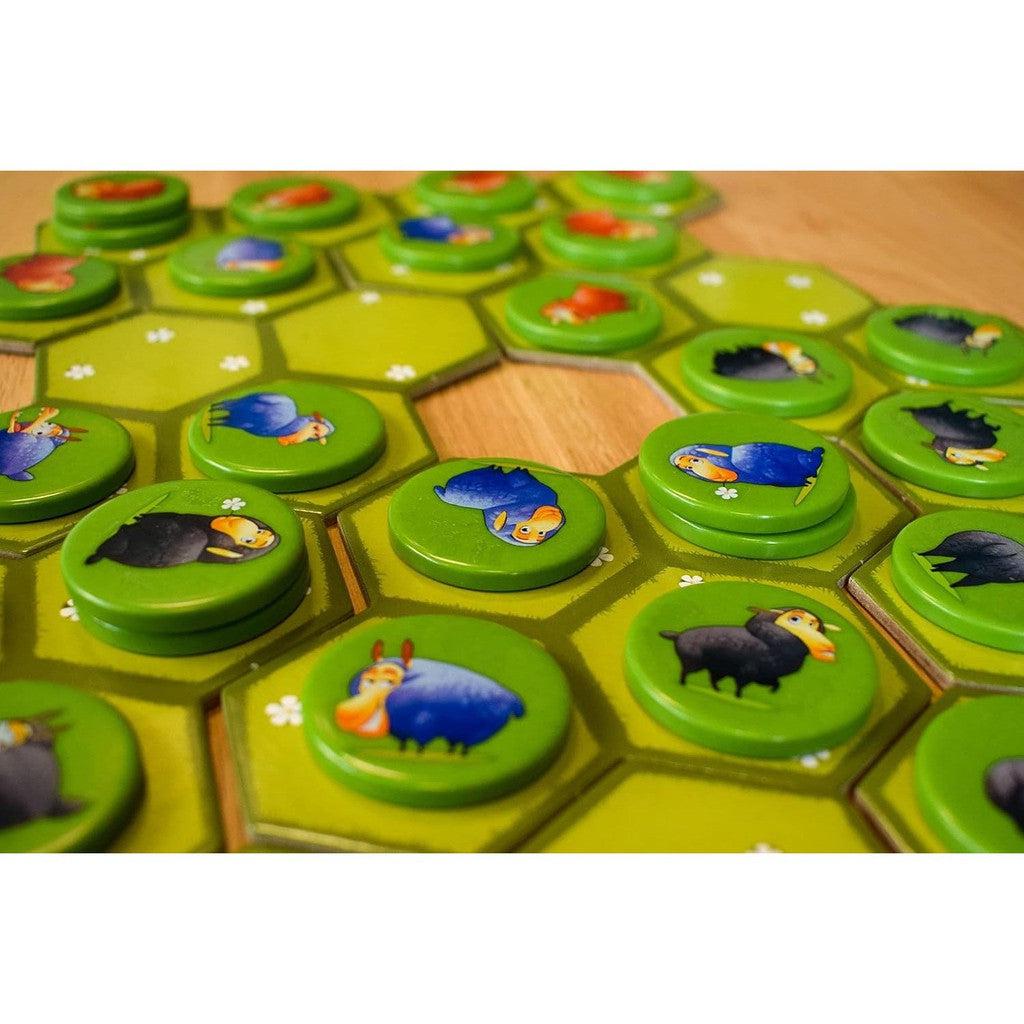 Hexagonal game tiles with stacked circular tokens featuring cartoon sheep in various colors make the Battle Sheep Game a delightful addition to your Toys &amp; Games collection. Enjoy colorful strategy with this unique offering from Blue Orange Games.