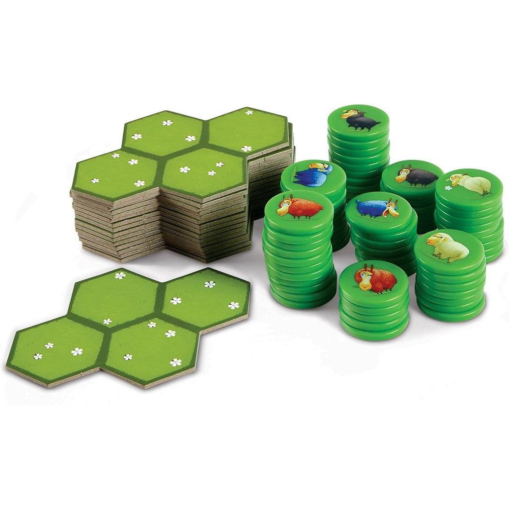 Stacked green game tiles and hexagonal boards, featuring charming sheep illustrations, set the stage for a delightful round of the Battle Sheep Game by Blue Orange Games.