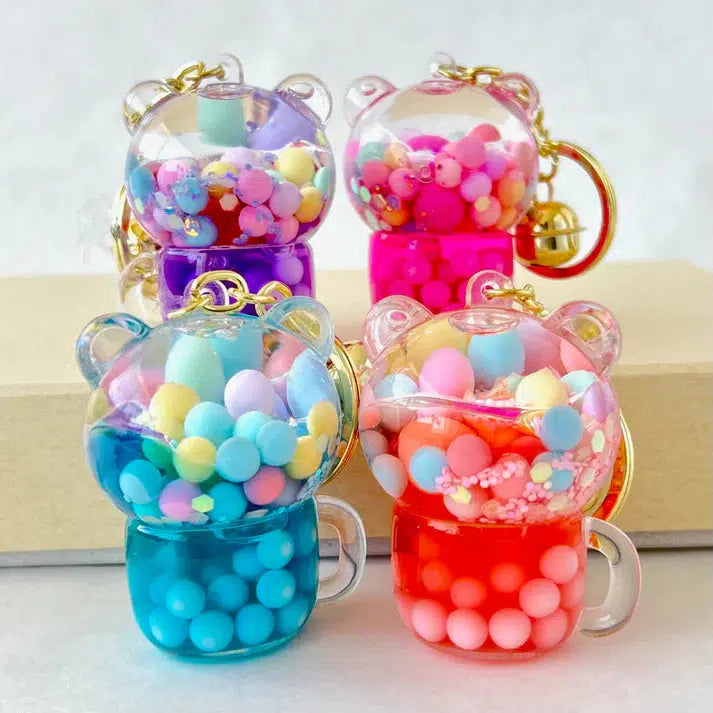 Five bear-shaped key charms, each filled with colorful beads like a playful bear boba floaty, positioned on a light surface.