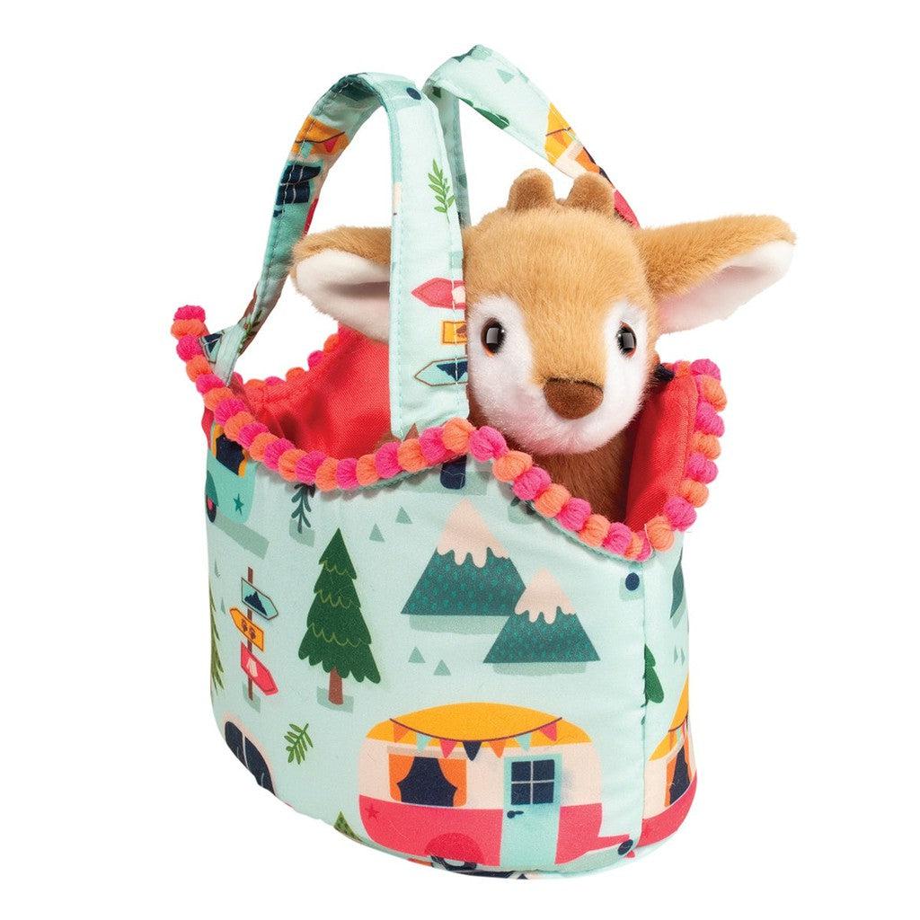 A stuffed animal fawn peeks out from a colorful fabric basket with a camping-themed pattern and pink trim, reminiscent of vintage caravans.