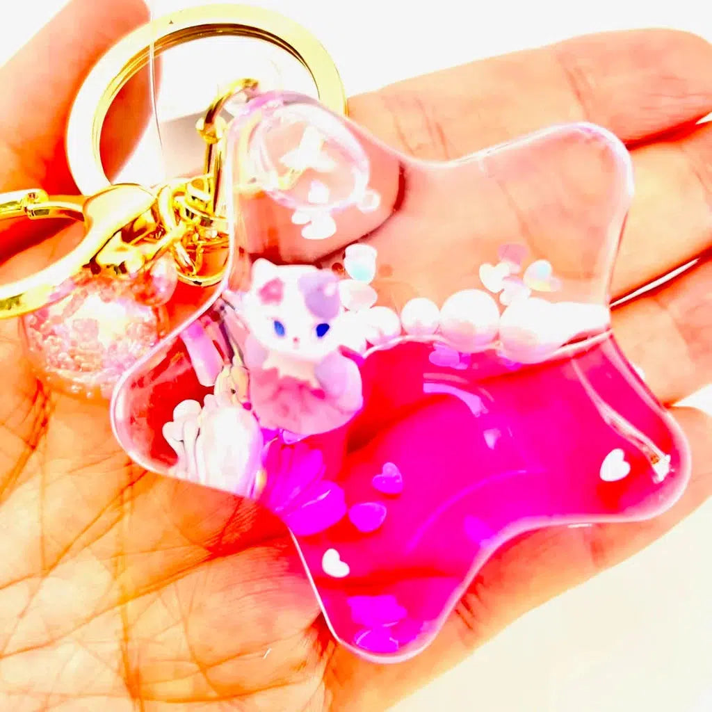 Close-up of a hand holding a star-shaped key charm, filled with pink liquid where silly animals and heart shapes float alongside a small cat girl figure inside.