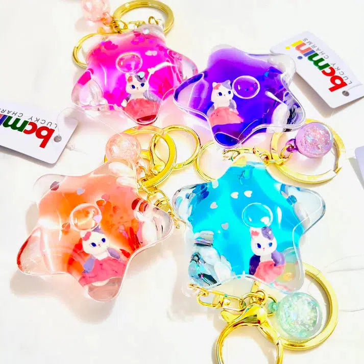 Four star-shaped key charms in pink, purple, orange, and blue feature silly animal figures inside. Perfect as a bag accessory, they're attached to golden rings adorned with decorative beads.