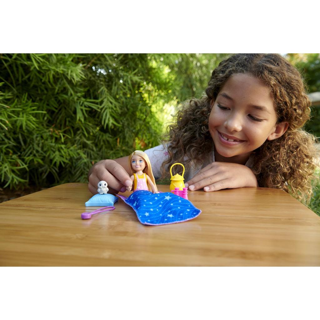 Young girl playing with doll and accessories outside.