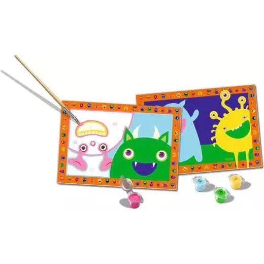 Two colorful drawings of cute monsters, one green and one yellow, surrounded by an orange frame with icons. A paintbrush rests on one, with three paint pots below—a perfect setup for kids at the Ravensburger Online Store to enjoy paint by numbers fun!.