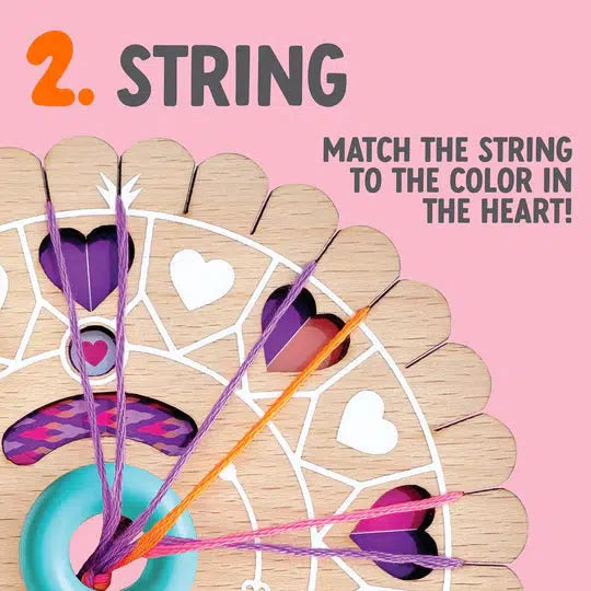 Wooden toy with colorful strings matched to heart-shaped slots. Text reads: "2. String. Match the string to the color in the heart!" Features a patent-pending design for a unique play experience. Background is pink.