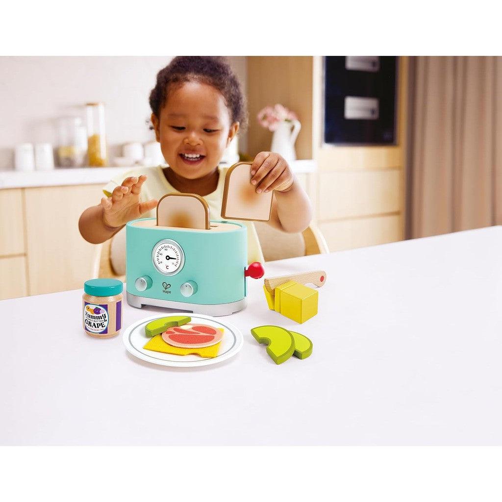 child playing with Hape ding and pop-up toaster