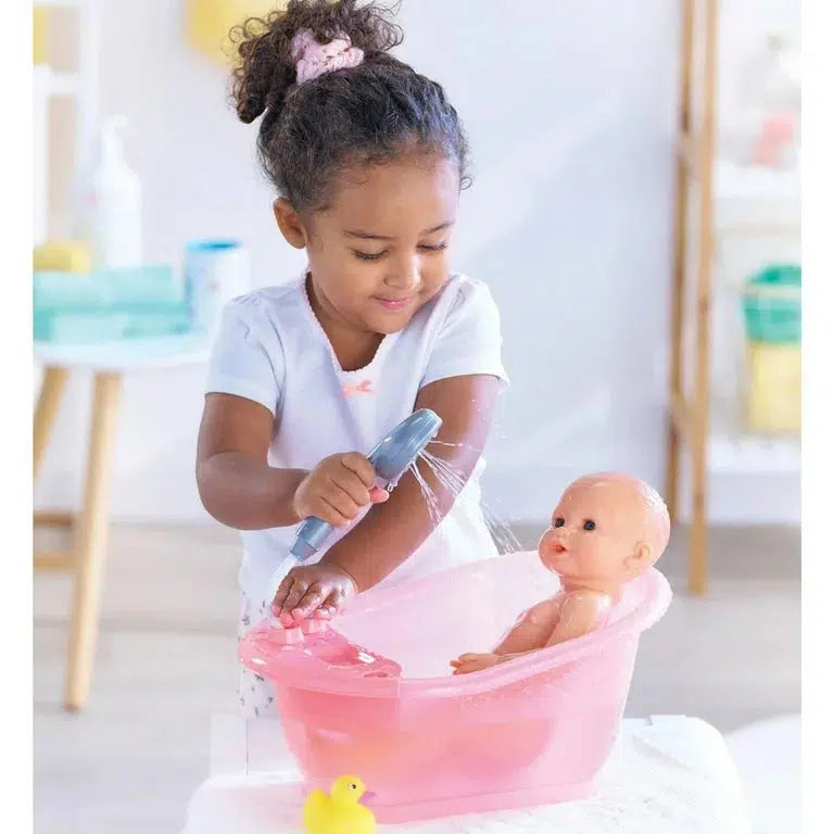 A child bathes a Corolle Doll in a pink tub, using a toy showerhead. Nearby floats a yellow rubber duck, creating the perfect Bathtub &amp; Shower playtime scene.