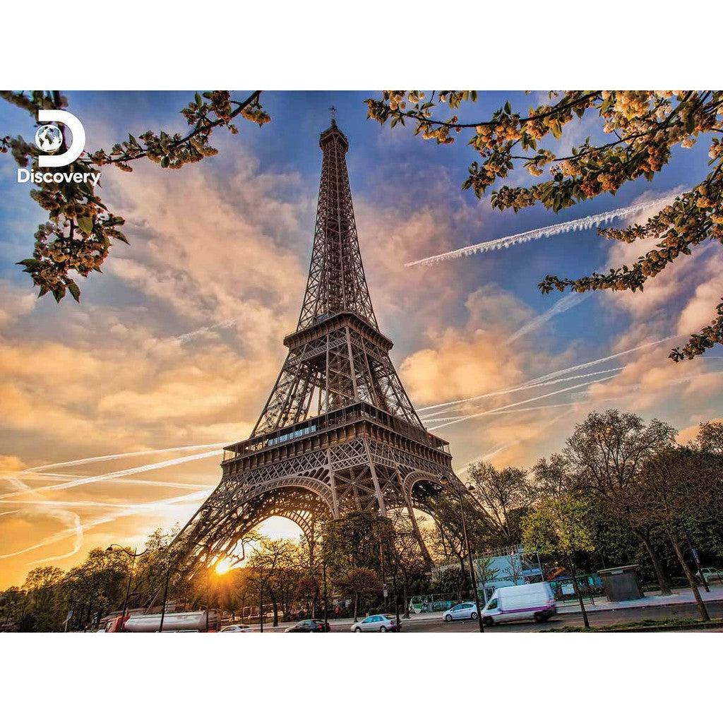 The Eiffel Tower in Paris stands majestic at sunset, framed by trees and contrails weaving a picturesque puzzle across the evening sky.