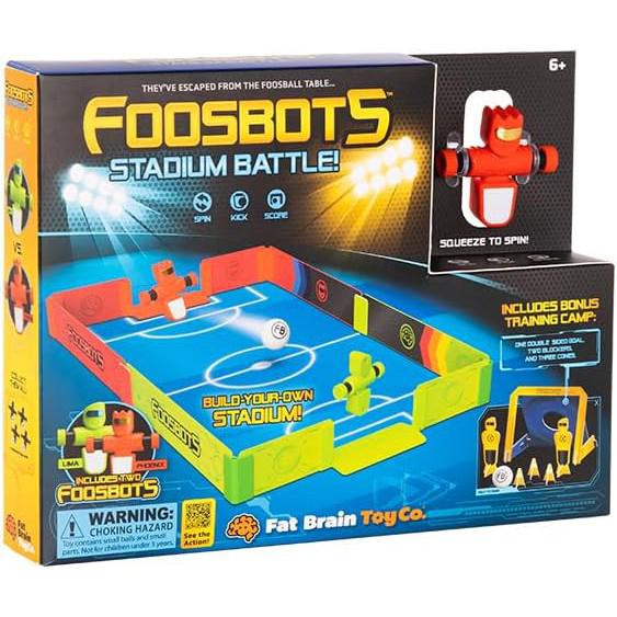 Introducing the "Foosbots Stadium Battle Set" from Fat Brain Toys—a vibrant box containing a colorful stadium, foosbots figures, and a training camp. Perfect for 2 player games, it's recommended for ages 6 and up.