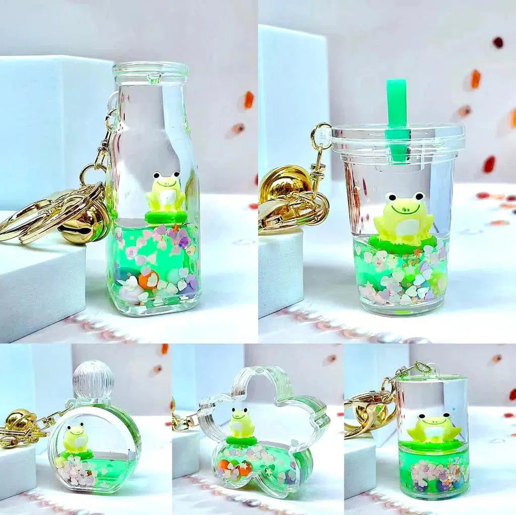 Keychains featuring silly animal figures like tiny frogs inside clear containers filled with liquid and colorful decorations, displayed on a white surface. These playful frog boba floaty key charms add a whimsical touch to your accessories.