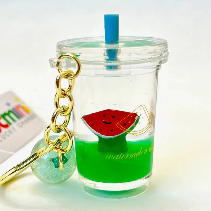 This keychain features a mini clear cup with green liquid, a whimsical watermelon slice design, a blue straw, and is adorned with a key charm chain enhanced by a green bead. Perfect for adding charm to your everyday look!