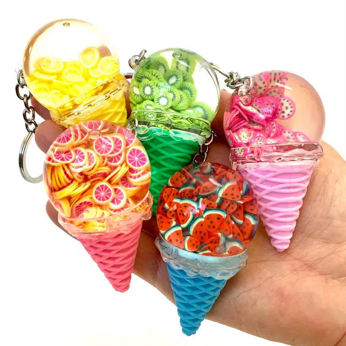 A hand holds five ice cream cone keychains, showcasing assorted designs with fruit motifs like lemons, kiwis, strawberries, oranges, and watermelons. Each key charm adds a playful twist to your collection.