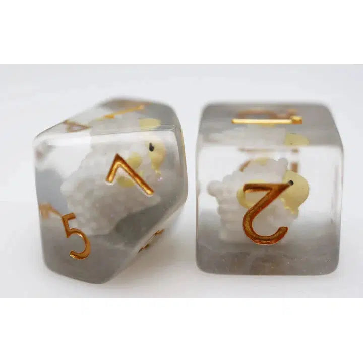 These two transparent six-sided dice, perfect for Dungeons and Dragons enthusiasts, feature gold numbers and tiny sheep figures embedded inside. Add a touch of whimsy to your role-playing games with these unique, enchanting dice.