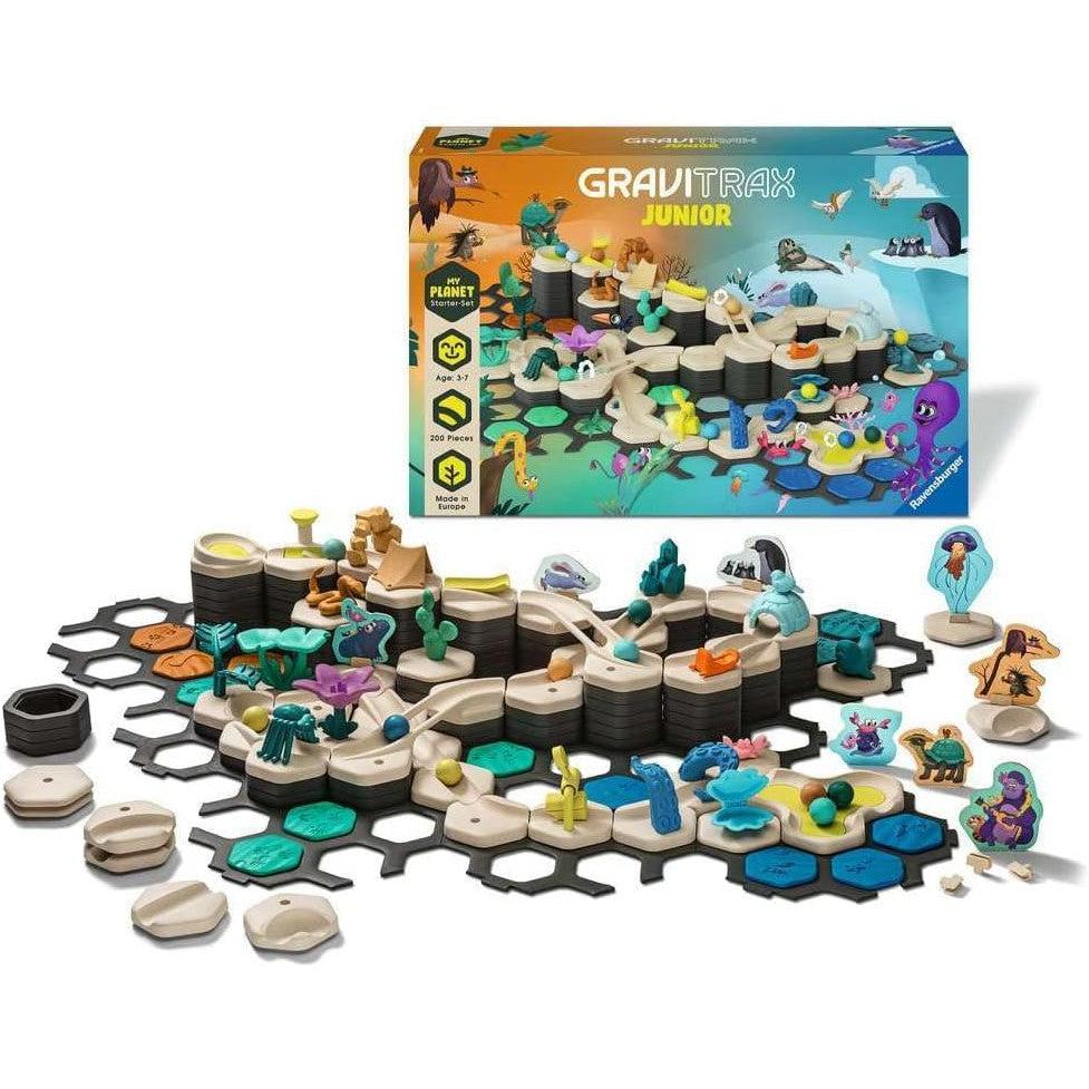 The Ravensburger GraviTrax Junior set showcases a dinosaur-themed landscape with an exciting preschool construction toy. Various pieces are assembled, offering a dynamic marble run experience. The packaging box is displayed in the background.