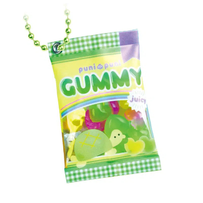 A packet of colorful gummy candies showcases assorted designs, including silly animals with turtle and lemon motifs on the packaging. It features a green plaid border and a beaded chain with a delightful turtle gummy key charm attached.