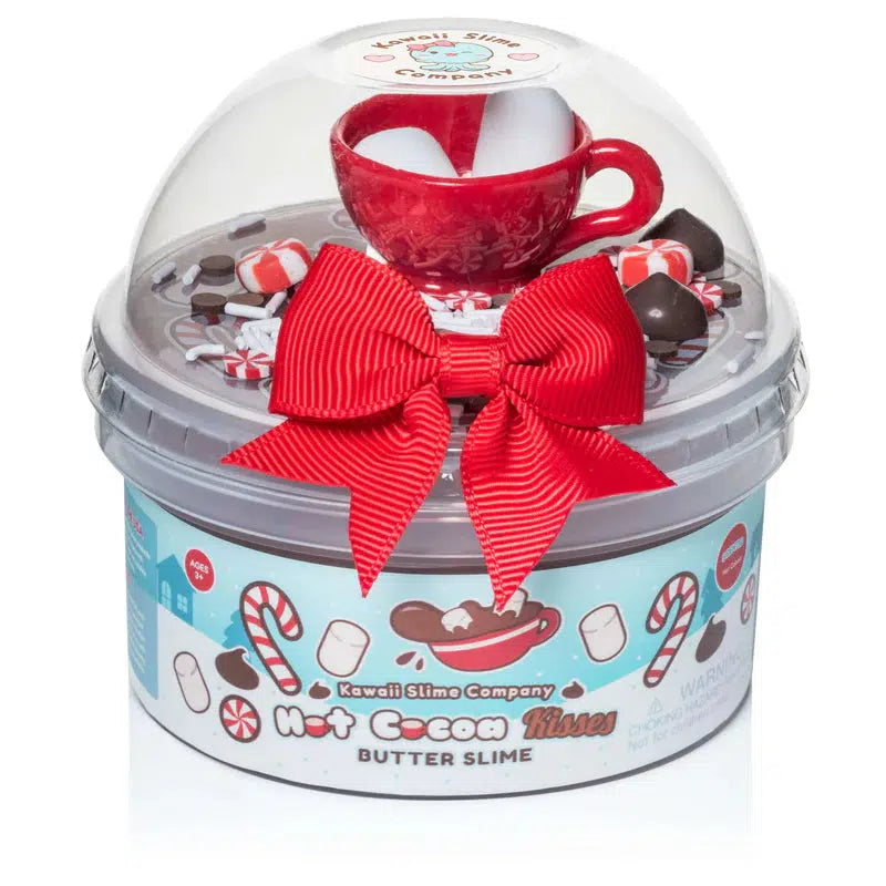 Container of butter slime labeled "Hot Cocoa Kisses," with festive decorations, a small red cup, and wrapped with a red bow under a clear dome lid.