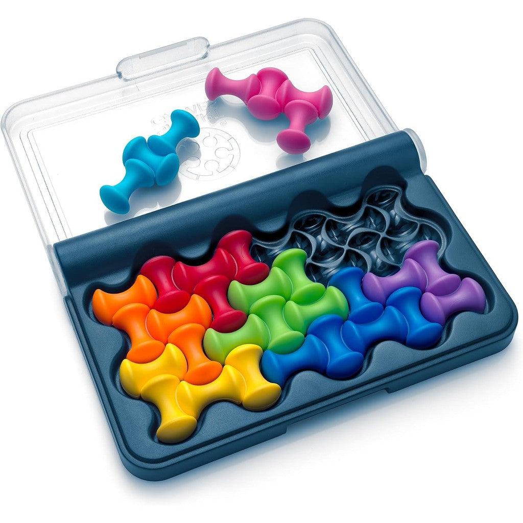 Colorful puzzle pieces, reminiscent of SmartGames' vibrant strategy games, are arranged in a case with an open lid, featuring red, pink, orange, yellow, green, blue, and purple components.