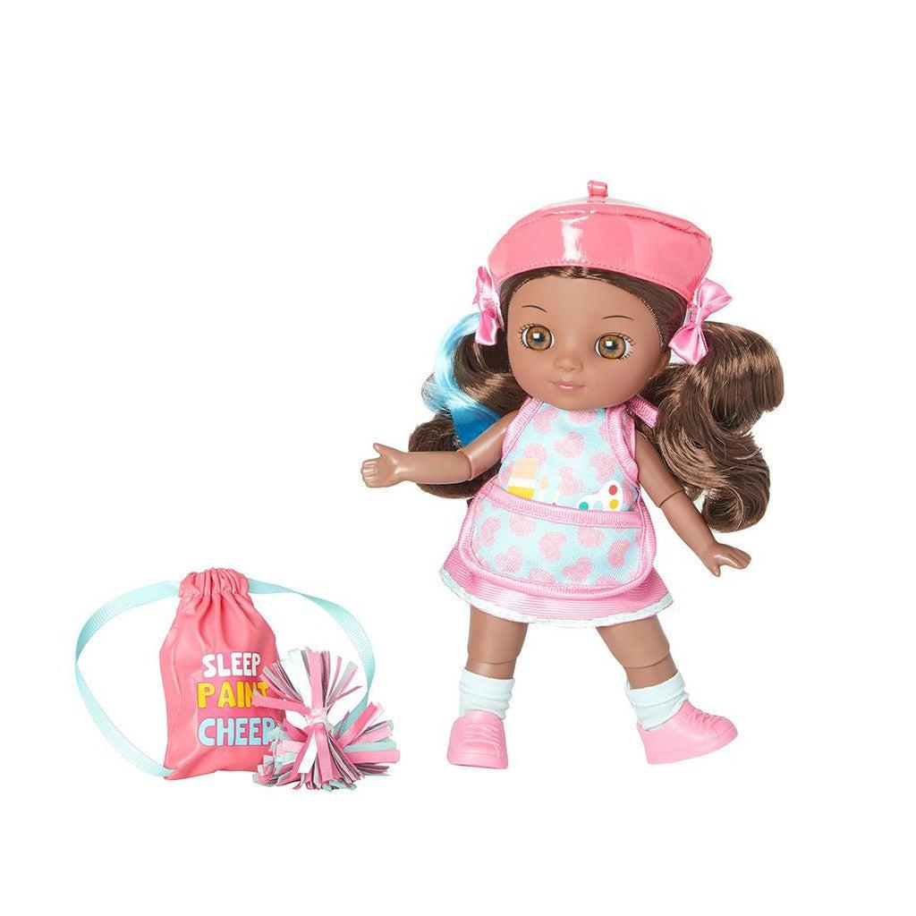 A cheerleader doll with curly brown hair, dressed in a pink outfit and hat, embodies the artist's touch in crafting outfits and accessories. She comes with a pink drawstring bag and pompoms, perfect for sparking imaginative play.