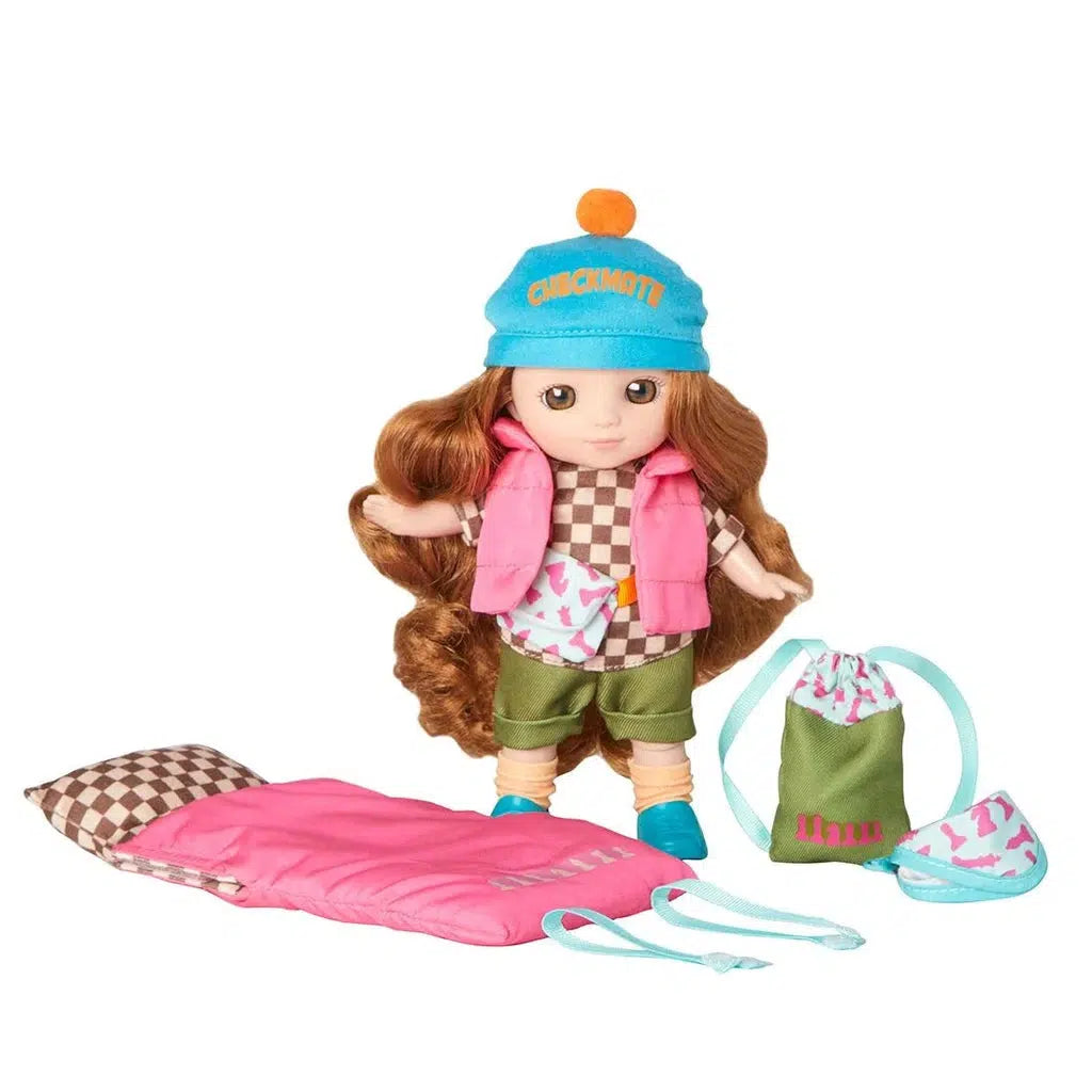 Toy doll with long brown hair, wearing a blue cap, pink vest, checkered shirt, green shorts, and blue shoes. Accessories include a pink sleeping bag for camping adventures, patterned backpack to carry essentials, and a cute sleeping mask for restful nights under the stars.