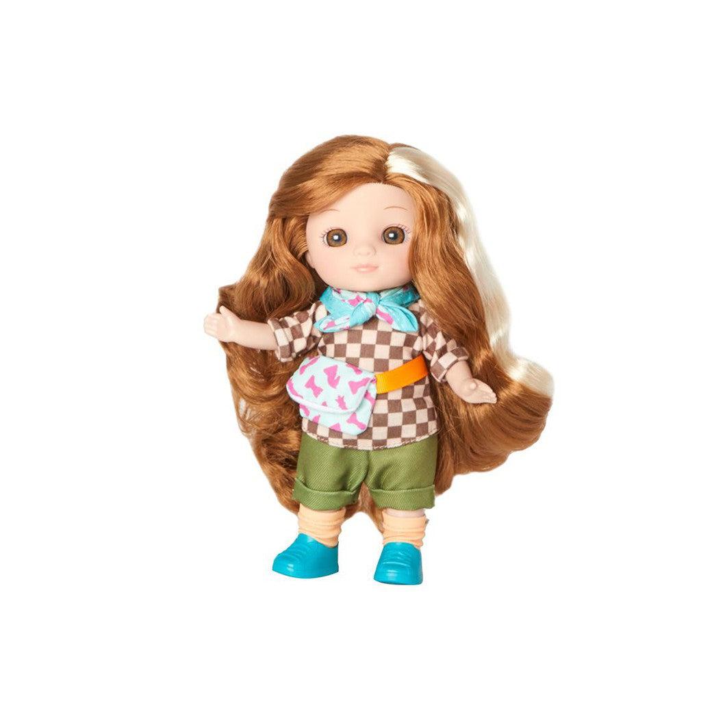 A doll with long brown hair dressed in a checkered shirt, green shorts, and blue shoes is ready for a camping adventure. Her look is completed with a small patterned bag, offering practical charm to her stylish outfits and accessories.