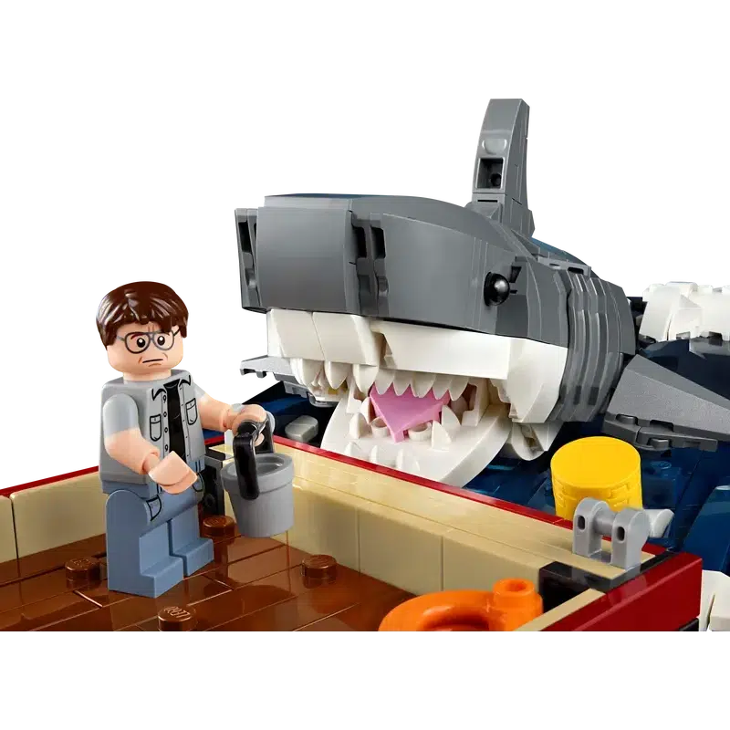 In this thrilling LEGO scene, reminiscent of Jaws movie memorabilia, a person on a boat clutches a bucket as they're menaced by a large, open-mouthed shark. A must-have collectible for fans of classic film adventures.