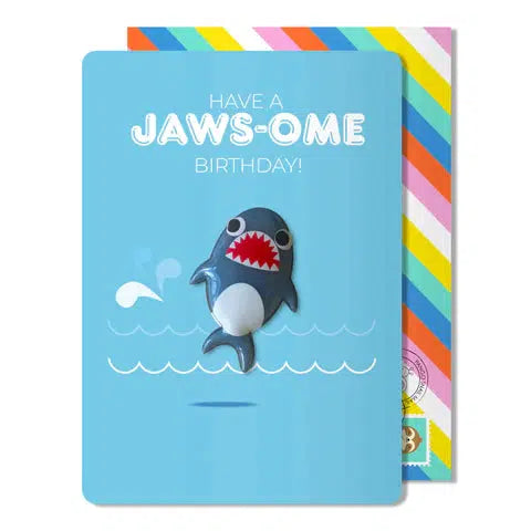 Blue birthday card with a cartoon shark magnet and a rainbow envelope. The card says "have a jaws-some birthday"