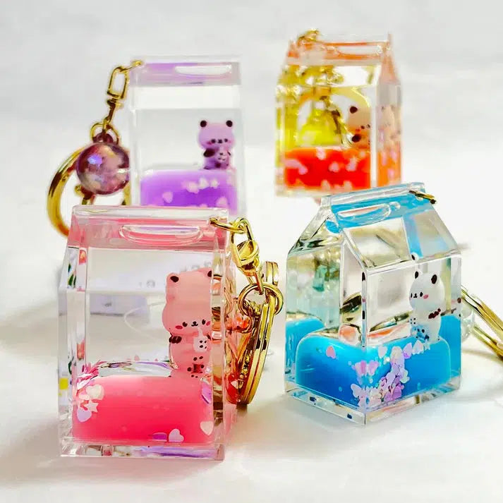 Four colorful house-shaped keychains with liquid-filled interiors, each containing small animal figures and decorative elements like flowers and confetti. These assorted designs, including a playful kitty milk carton, add a whimsical touch. Perfect as a charming key charm accessory!