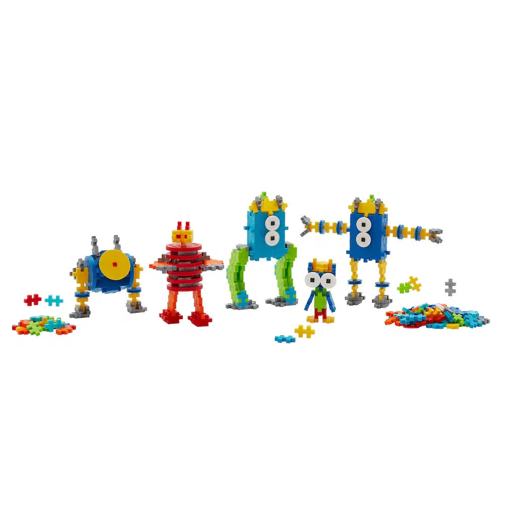 Colorful toy robots, uniquely assembled from Plus-Plus interlocking plastic pieces, with additional creative building pieces scattered around.