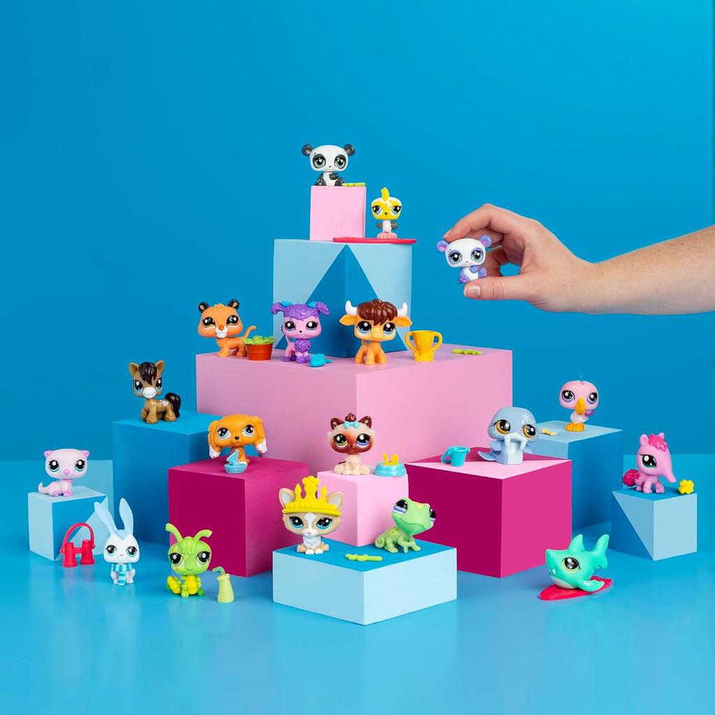 A hand sets a toy panda on a stack of cubes covered with tiny tony animals