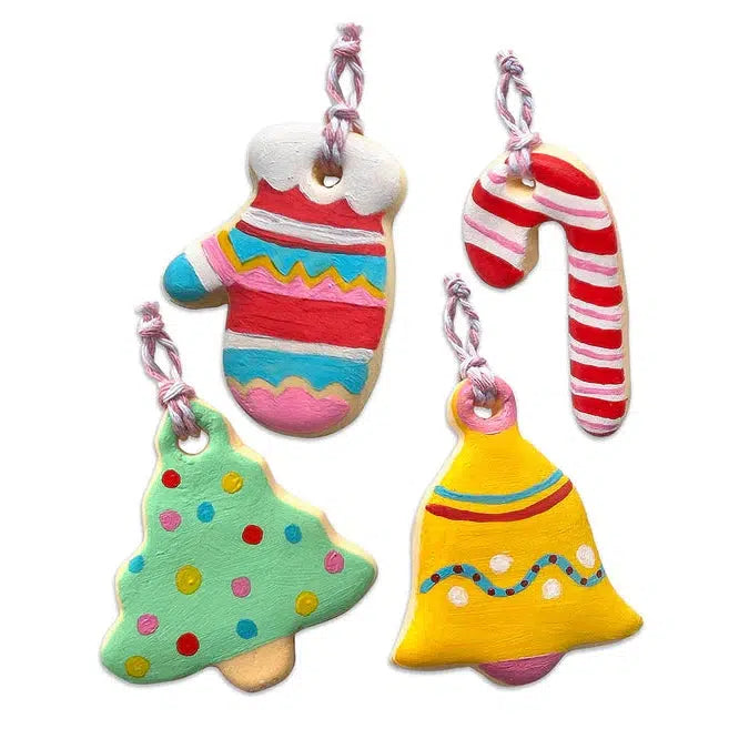 Four colorful Christmas ornaments, including cookie-shaped designs like a mitten, candy cane, tree, and bell adorned with decorative patterns and pink twine loops. These delightful decorations are perfect for a festive activity using air-dry clay.