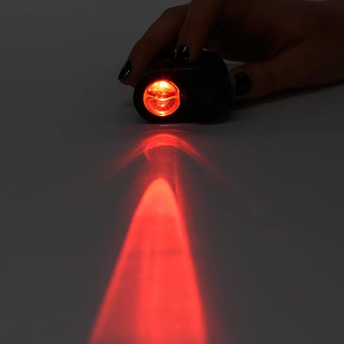 A hand holding a SpyX Micro Spy Scope shines a red beam of light onto a flat surface, blending sophisticated spy gadgets with simplicity.