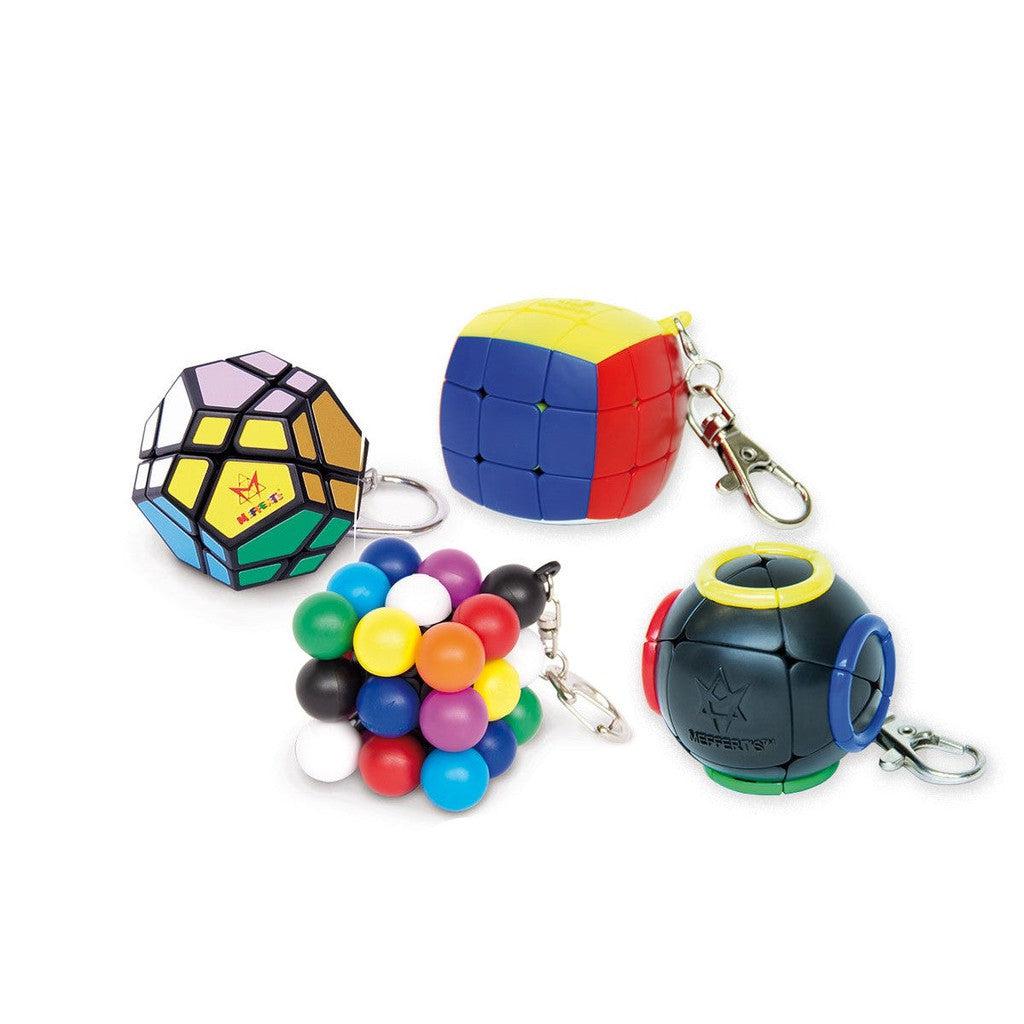 Four puzzle keychains: a dodecahedron, a block with red, blue, and yellow faces, a cluster of colorful spheres, and a black sphere with colored sections.