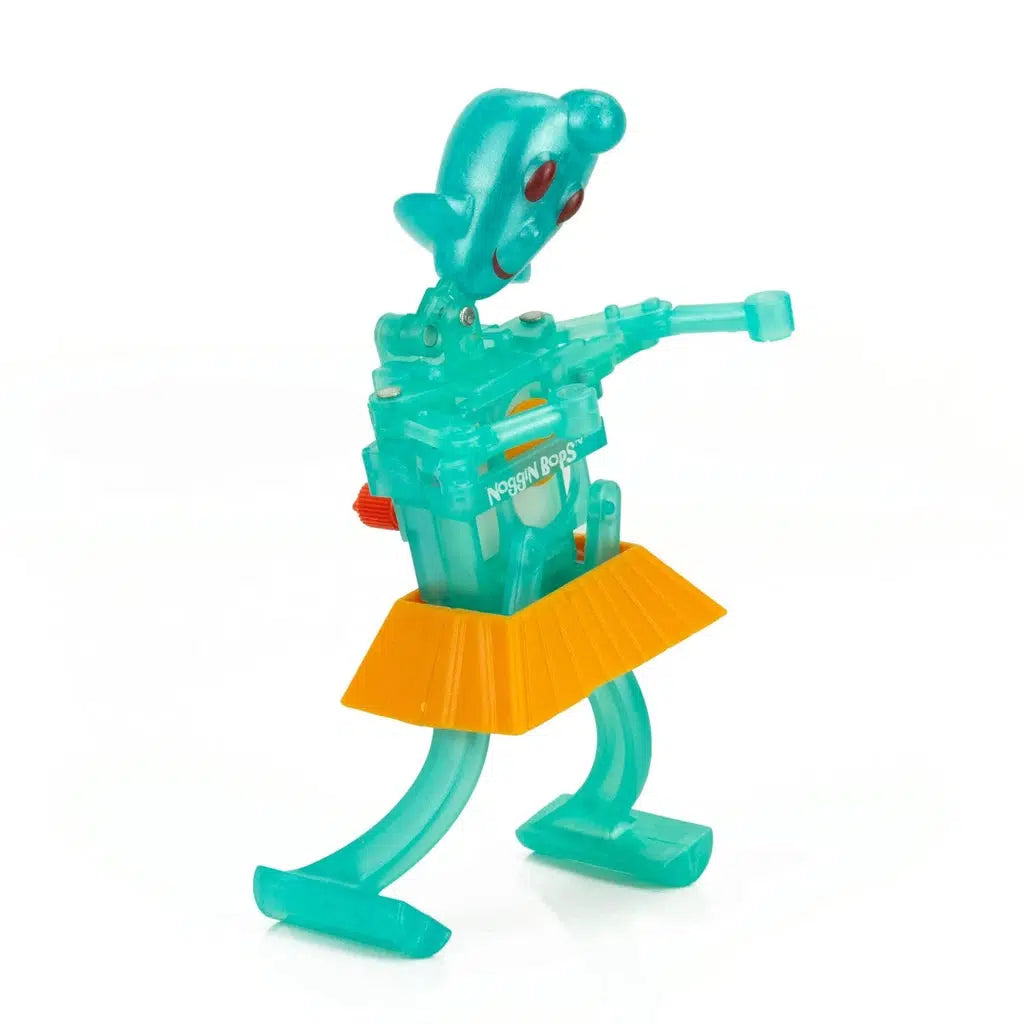 A transparent green plastic toy robot with big eyes, an orange skirt-like detail, and adjustable arms stands upright, ready for adventure. This interactive children's toy brings excitement and imagination to life.