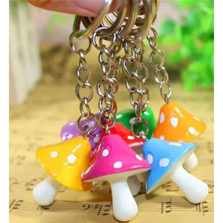 Colorful mushroom key charm with polka dots attached to metal chains are displayed against a blurred background.