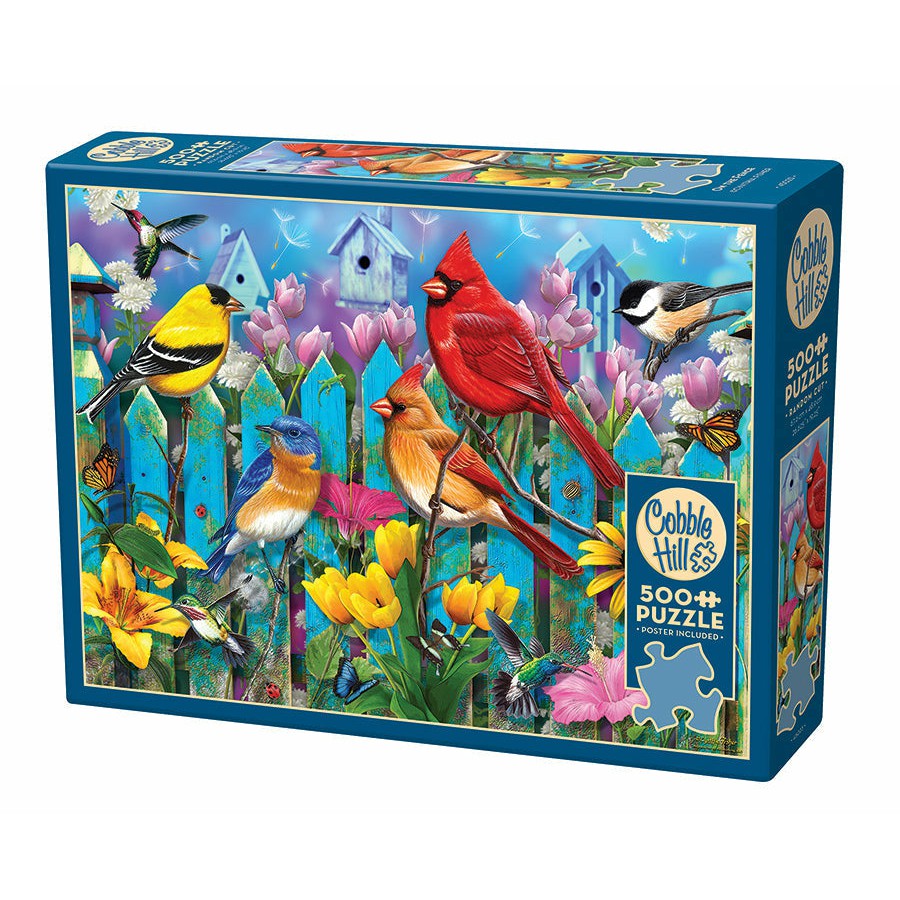 Puzzle box featuring a vibrant illustration of various birds perched on a fence with colorful flowers and birdhouses in the background. The puzzle contains 500+ pieces.