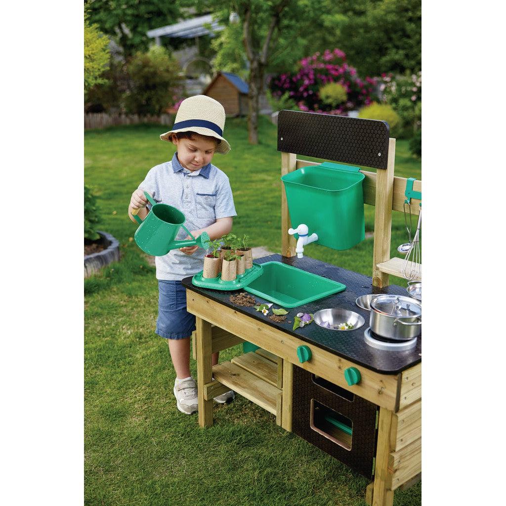 child playing with outdoor kitchen, watering plants