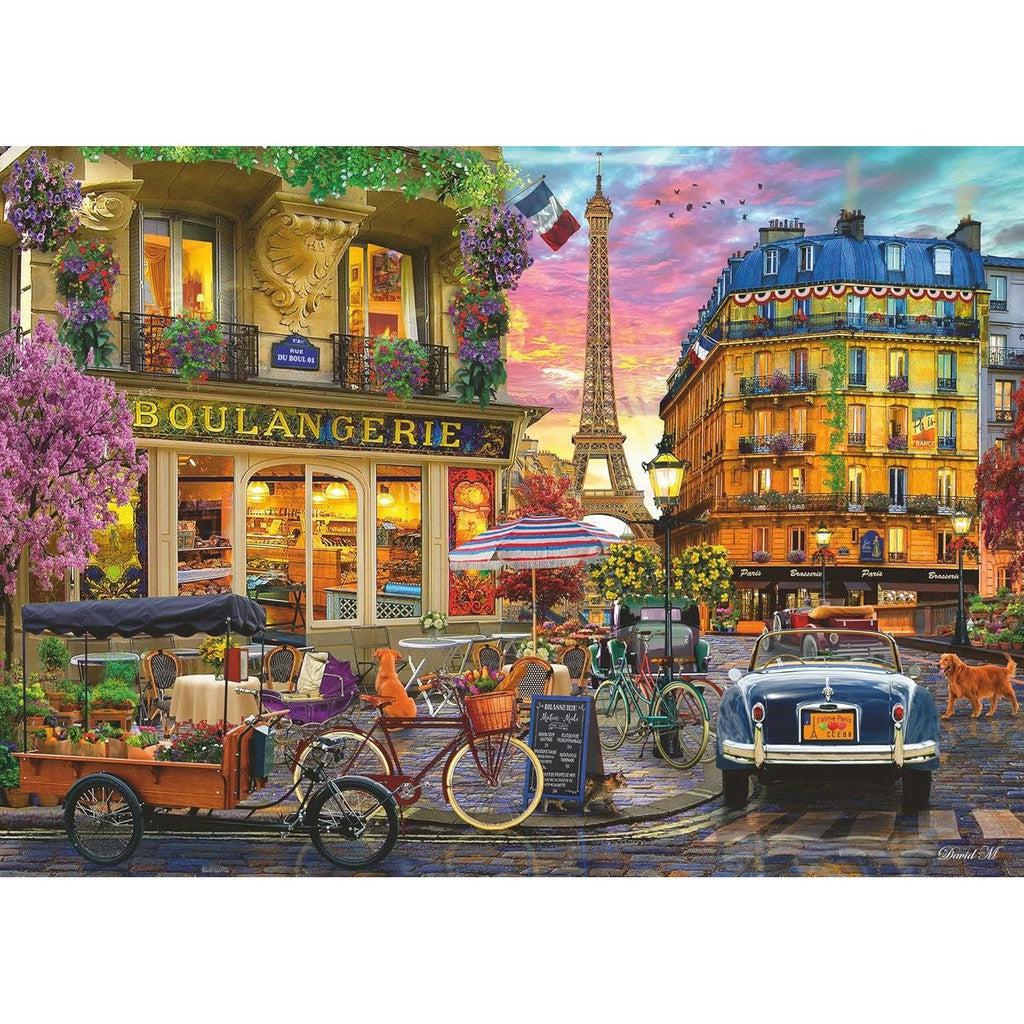 Experience the charm of Paris at Sunrise with this colorful 1000-piece Ravensburger puzzle featuring a vibrant street scene. Delight in the boulangerie, café tables, vintage car, and bicycles with the Eiffel Tower in the background, adorned by bright floral decorations and lively buildings.