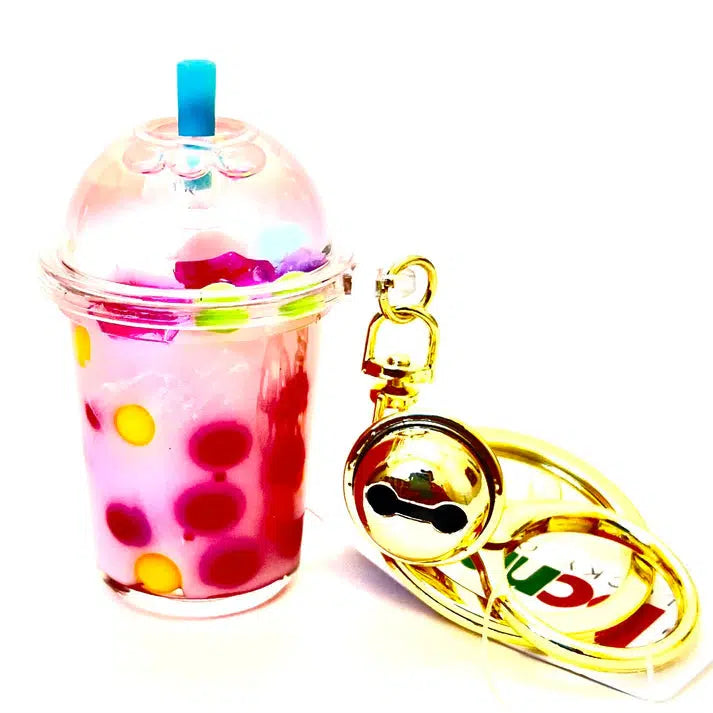 This whimsical pink bubble tea keychain, featuring colorful beads inside and a blue straw, doubles as a BOBA FLOATY KEY CHARM. It's completed with a gold bell charm for that extra touch of fun.