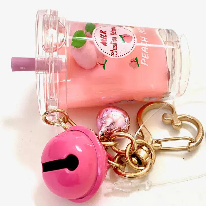 A keychain showcasing a pink boba drink charm with a straw, complemented by a pink bell and a gold heart-shaped clip, adds playful flair. The assorted designs ensure each piece is unique, perfectly blending fun elements with the key charm's elegance.