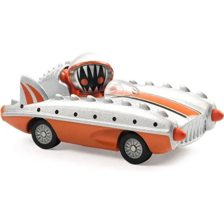 A toy car with an orange and silver design, featuring a whimsical character with a piranha jaw in the driver's seat. The go-kart has fin-like structures and round wheels, accented with metallic paint for extra flair.