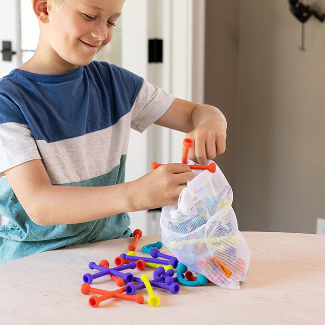 Child loading Plip Kit toys into a washable bag