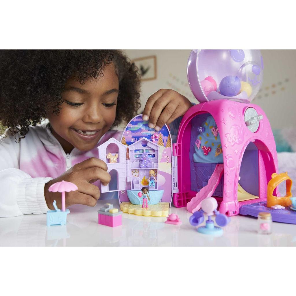 Scene of a little girl smiling while playing with the bear gumball machine.