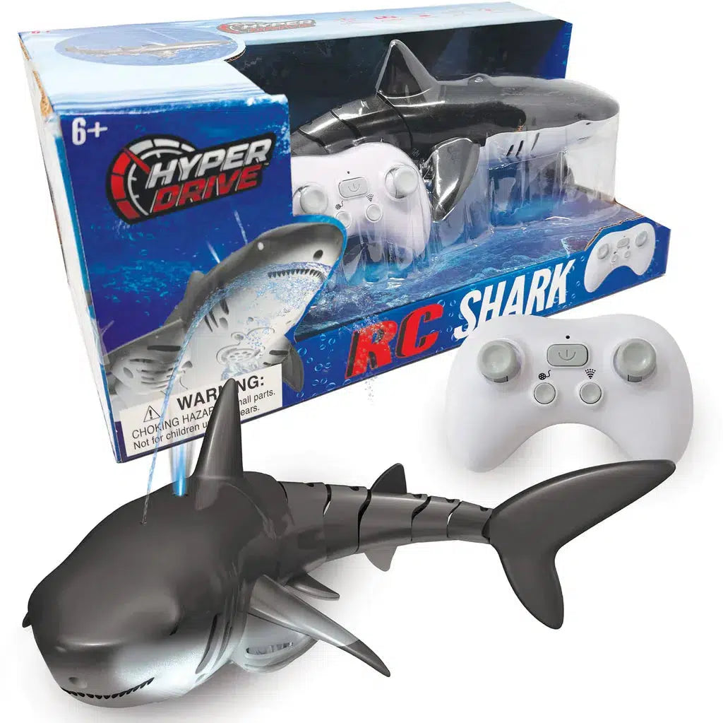 A remote-controlled toy shark package by THiN AiR Brands titled "Hyper Drive RC Shark" showcases a black shark figurine beside a white controller. Perfect for shark lovers, it includes an age suggestion of 6+.