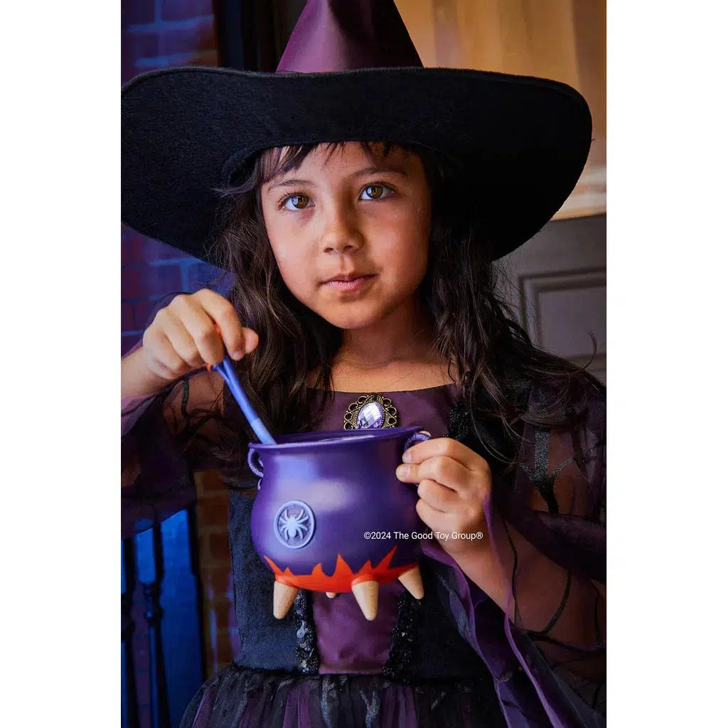 Small girl dressed as a witch playing with witch's Brew play set