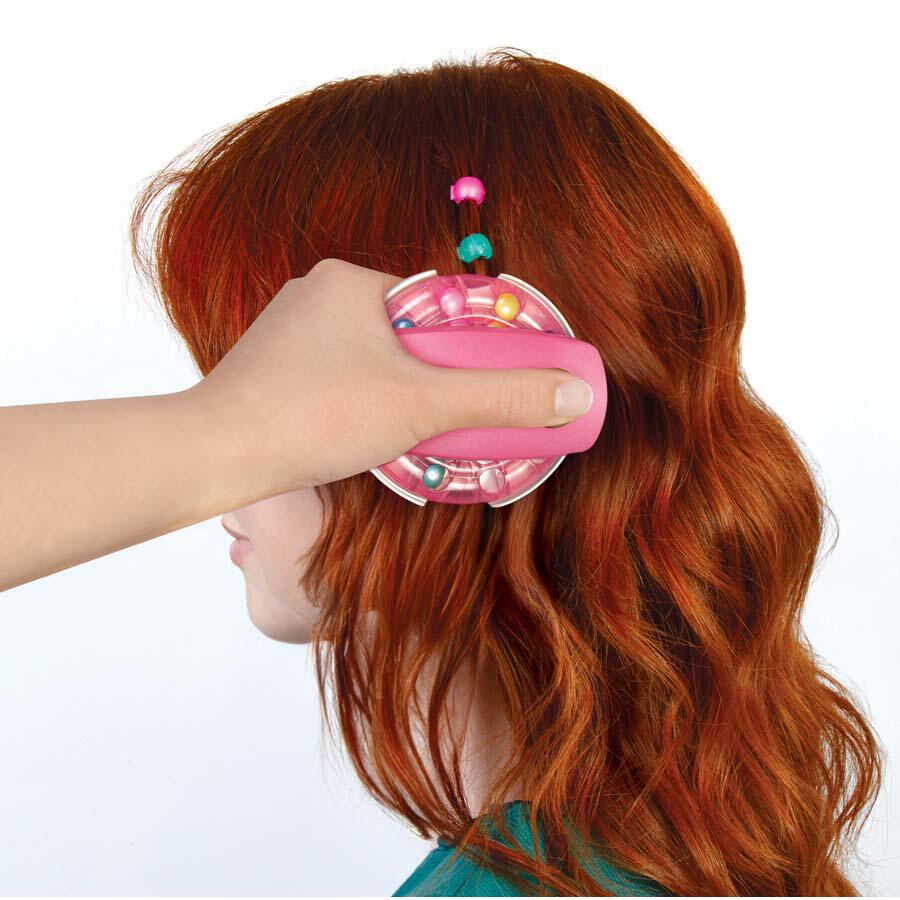 A person using a pink handheld scalp massager on the head of a woman with red hair, adorned with colorful beads, evoking creativity akin to the Make It Real Snap 'N Glam Hair Styling Set.