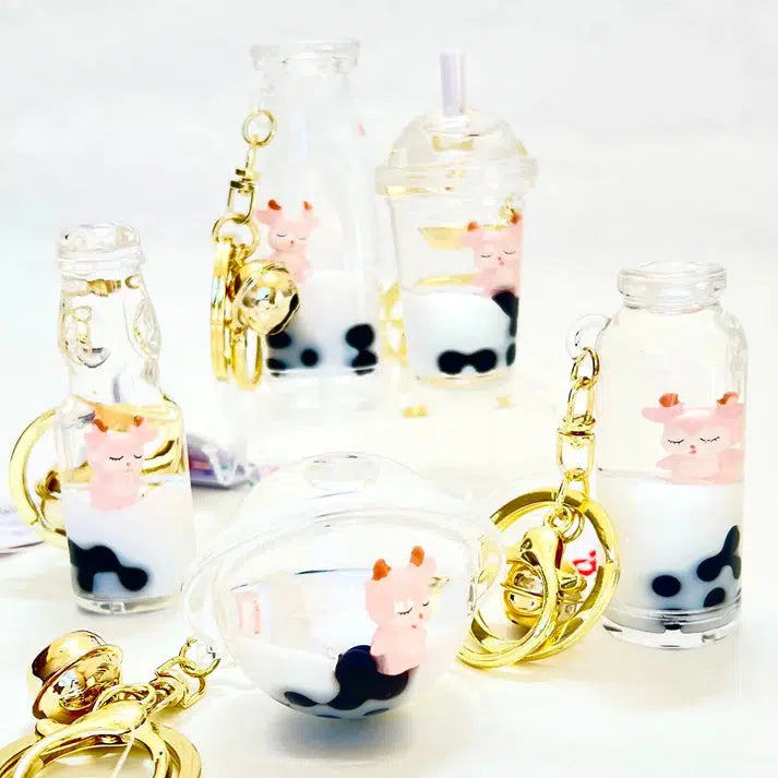 Adorn your accessories with this key charm featuring assorted designs of milk tea bottle-shaped keychains, where silly animals in pink playfully float inside, surrounded by delicate pearls.