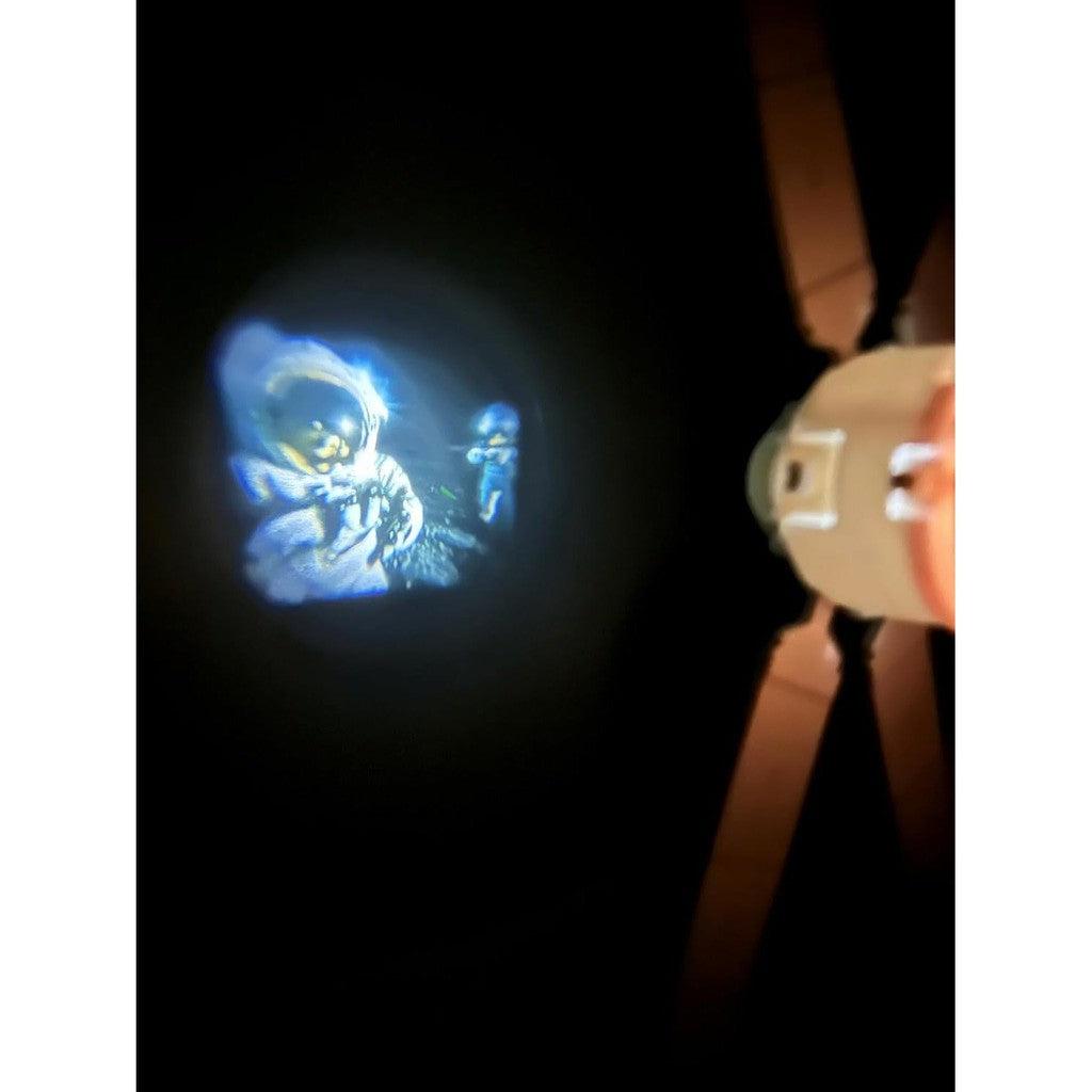 A NASA Future Explorers astronaut image is projected onto a dark ceiling next to a ceiling fan, inspiring dreams of space exploration.