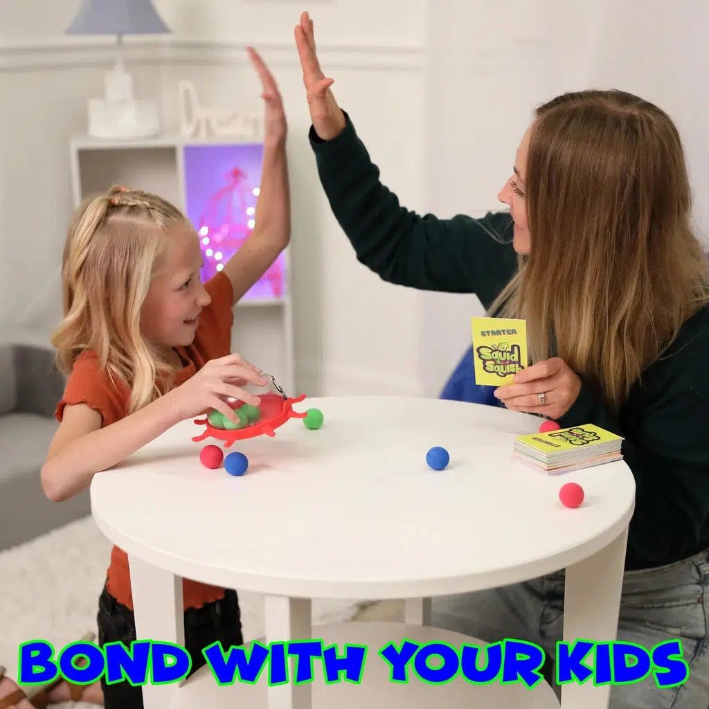 An adult and child sit at a small table high-fiving, surrounded by colorful balls and an educational card game. Text reads, "BOND WITH YOUR KIDS IN A COLOR-MATCHING ADVENTURE.