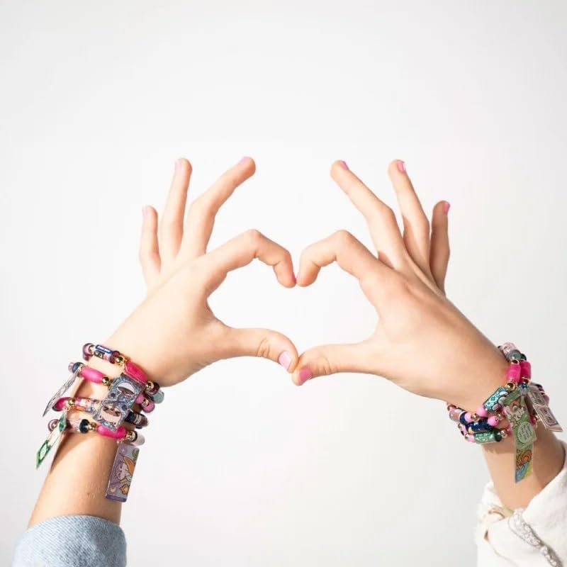 Two hands form a heart shape against a white background, their wrists adorned with colorful bracelets and charms. Among these is a unique wearable sticker toy bracelet, adding an extra touch of flair.